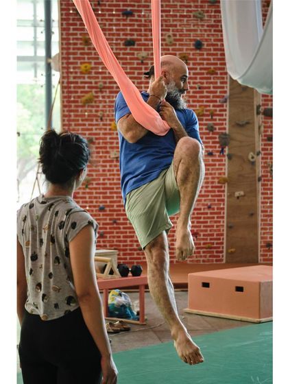 An instructor demonstrates a climbing technique on the hammock, showing how Vayu Yoga also builds upper body and grip strength.