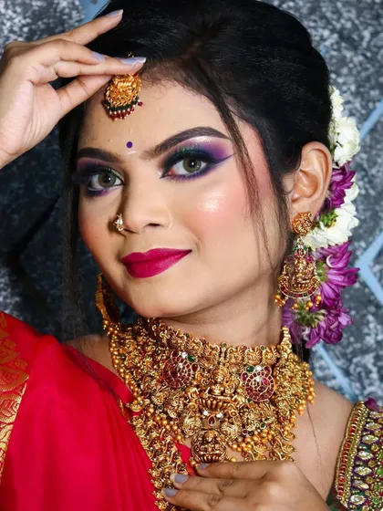 A confident portrait of the South Indian bride, her hand gracefully touching her maang tikka, drawing attention to the intricate jewelry.