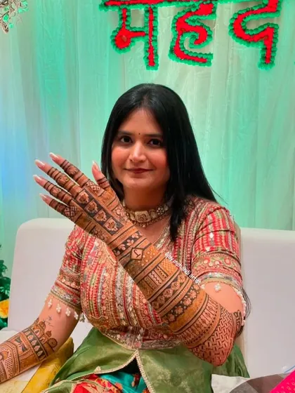 A smiling client showing off one of her mehndi-covered hands.
