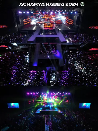 An aerial top-down shot capturing the immense crowd and spectacular stage lighting at Acharya Habba 2024. This perspective, only possible with professional drone videography, shows the sheer scale of the event and the energy of the audience.