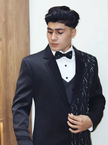 This black tuxedo features a lapel with silver wave embroidery. It's a modern, artistic touch for a formal outfit.