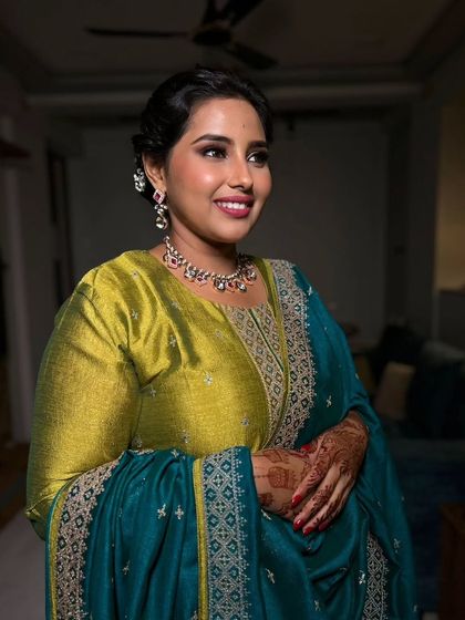 A sophisticated and elegant look for a wedding ceremony or reception. The makeup is clean and defined, with a bold lip that complements her beautiful teal and lime green outfit.