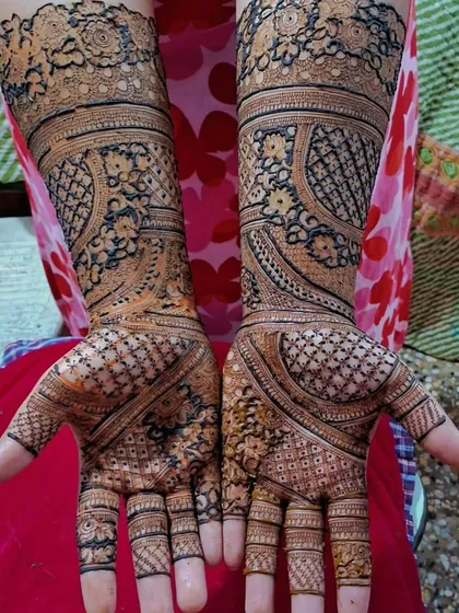 A lovely engagement mehendi with full coverage. The design uses a mix of checkerboard patterns, floral elements, and leafy vines for a rich and textured look.