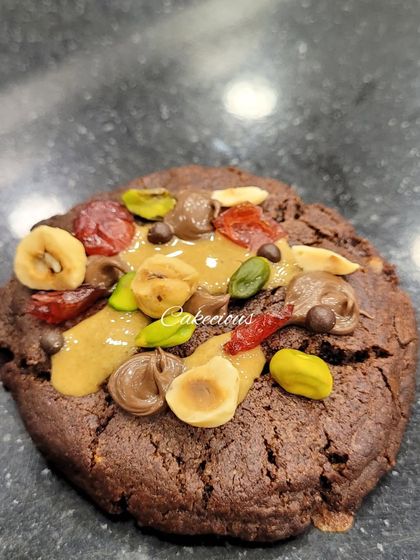 A close-up of my dark chocolate overload cookie. It's packed with nuts, dried fruit, and chocolate chunks for a truly decadent treat.