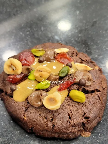 A close-up of my dark chocolate overload cookie. It's packed with nuts, dried fruit, and chocolate chunks for a truly decadent treat.
