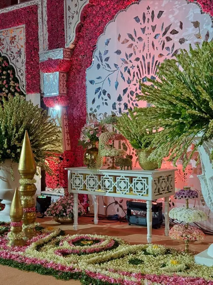We use flowers to create art on the floor. This enchanting detail shows a floral rangoli and traditional decor elements set against a backdrop of flower-laden walls and carved panels. 🌸❤️