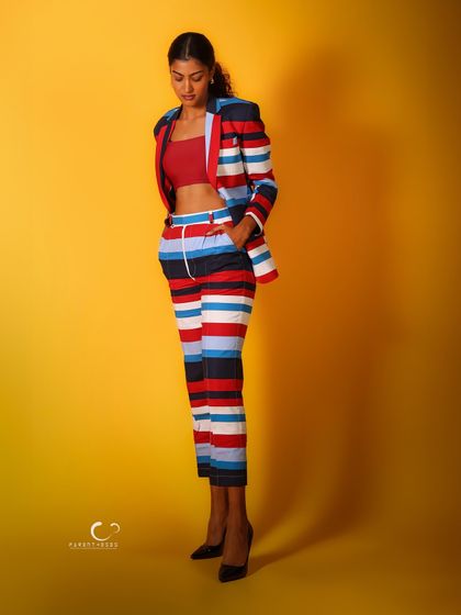 A contemplative, full-length pose that showcases the entire outfit. The simple background keeps the focus on the striking colors and patterns.