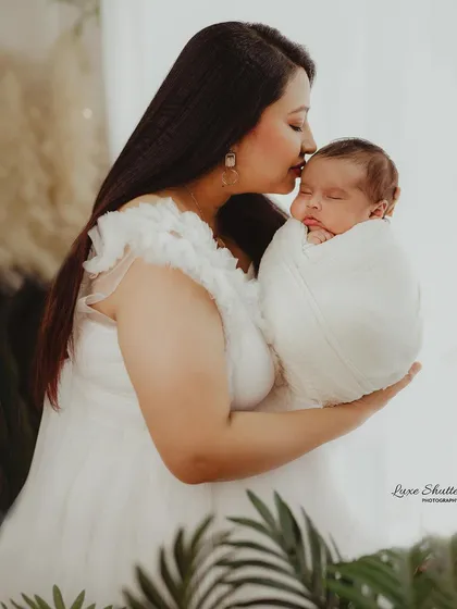 A mother's tender forehead kiss for her baby, a moment filled with emotion and love.