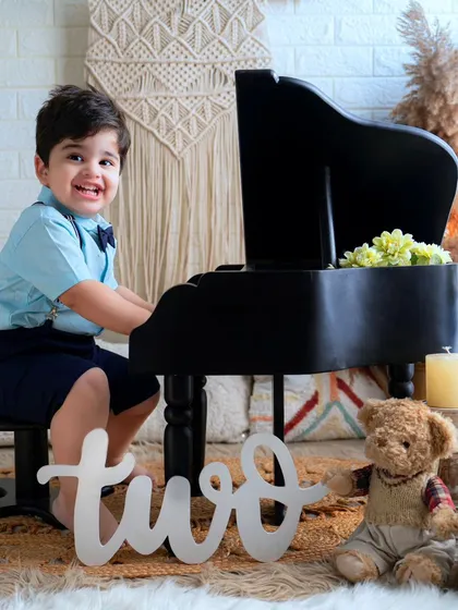 Celebrating two with music and smiles. This happy little boy is having a great time at his second birthday photoshoot with the miniature piano.