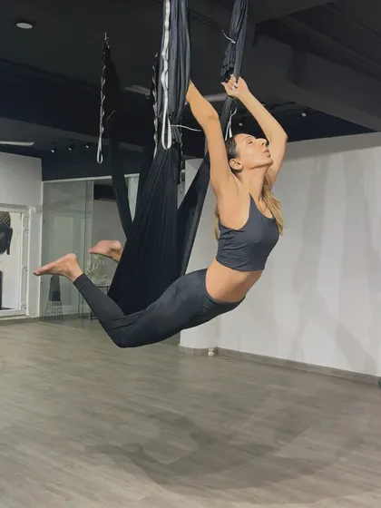 A graceful flying pose, demonstrating the feeling of weightlessness and freedom that aerial yoga provides.