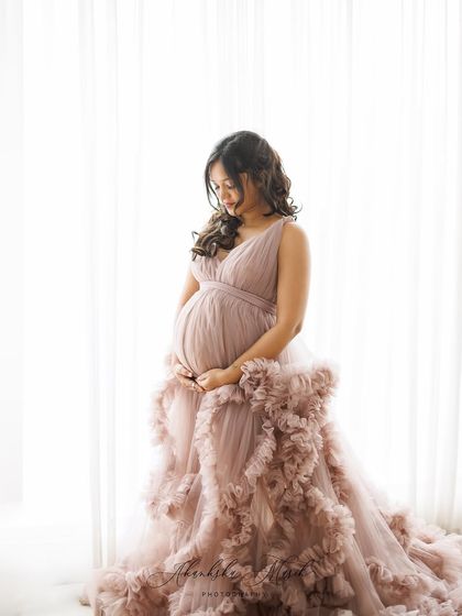 A soft and dreamy portrait by the window, with the mother-to-be in a mauve ruffled gown, bathed in natural light.