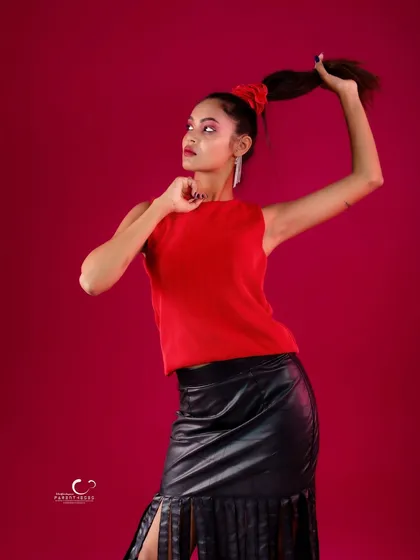 A dynamic and playful pose in a striking red and black outfit. The high ponytail and fringed skirt add a sense of movement and fun.