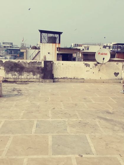 Before: An empty rooftop with a satellite dish and weathered walls. This space is ready for a complete makeover.