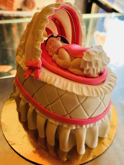 A close-up of the incredibly detailed, hand-sculpted baby in a bassinet cake topper.