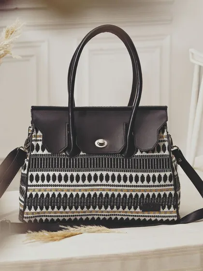 A beautifully styled shot of a patterned handbag on a table with dried pampas grass. This creates a bohemian, chic aesthetic that elevates the product.