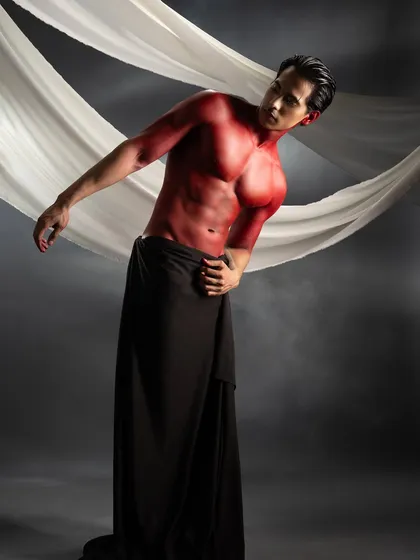 This conceptual shoot involved applying vibrant red body paint to create a powerful, statuesque look. I used slicked-back hair to keep the focus on the defined musculature and the stark contrast between the red paint and the dark draping.