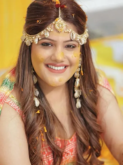 A happy, smiling portrait of Ishita, her face covered in haldi. This picture captures the pure joy of the ceremony.