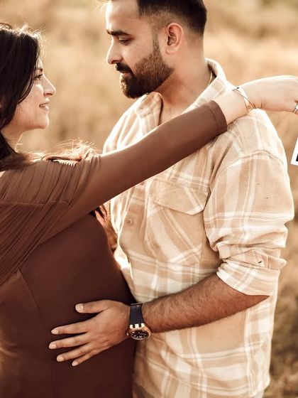 The couple embraces in a golden field, she holds the sonogram pictures, and they look at each other with love. A perfect blend of romance and anticipation.