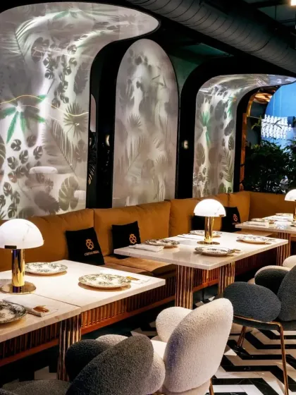 The curved banquette seating follows the organic shapes of the wall panels, creating a soft and inviting dining area. The mix of chair styles and textures adds visual interest and sophistication.