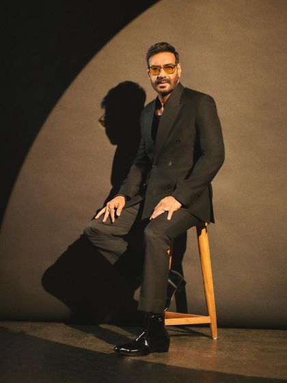 A spotlight shot of Ajay Devgn in a custom double-breasted black suit, exuding pure movie star charisma for an awards night.