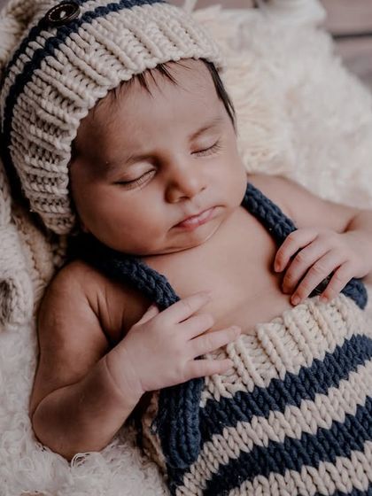 Cherishing the early days. This close-up shot captures the peaceful expression of a sleeping newborn in a cute, knitted outfit.