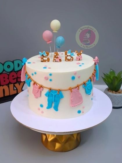 A simple and elegant baby shower cake with a clothesline theme and cute "BABY" blocks on top.