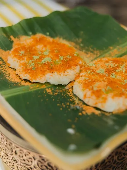 My Tatte Idli, or plate idli, is a soft, fluffy, and larger version of the traditional idli. Served on a banana leaf and dusted with spicy podi, it's a simple, authentic, and comforting dish.