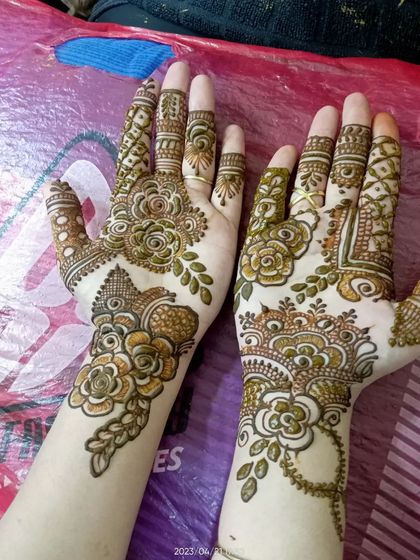 This design mixes bold floral work with delicate leafy trails and detailed finger patterns, creating a balanced and beautiful fusion look.