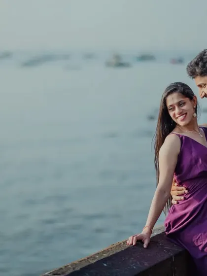 A happy, candid moment by the Mumbai waterfront. The sea and the distant boats provide a classic urban backdrop for a relaxed and romantic pre-wedding portrait.