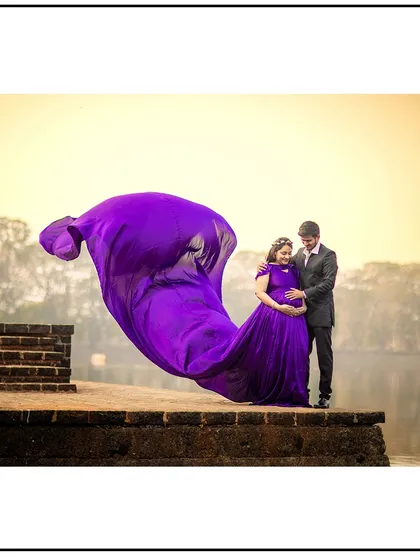 The wind creates a beautiful, swirling shape with the purple gown in this artistic couple's portrait.