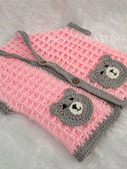 This pink and grey waffle-stitch sweater vest is perfect for layering. It's designed to be sleeveless for easy movement and features two adorable bear-face pockets for a playful touch.