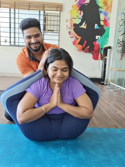 A moment of achievement in Yoganidrasana (Yogic Sleep Pose). My gentle assistance helps the student comfortably settle into this complex forward bend, showcasing our supportive teaching style.