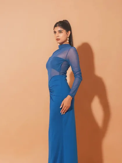 A side profile of the blue dress look. The clean lines of the makeup and the sleek ponytail create a very polished and high-fashion aesthetic.