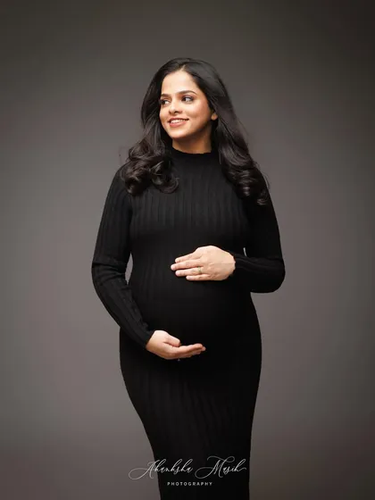 A classic and elegant portrait in a simple black dress, capturing a gentle, knowing smile.