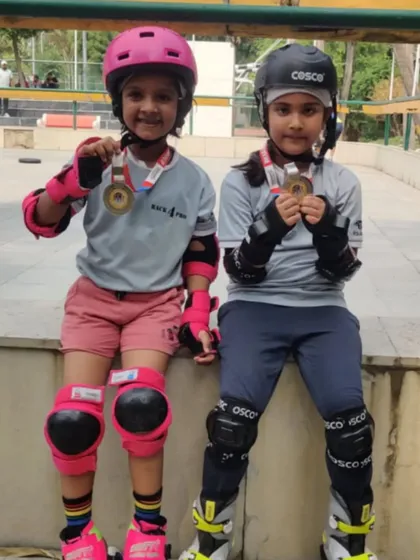 Two of our young skaters in full safety gear, proudly showing off their medals. This image perfectly captures our dual focus on safety and achievement.