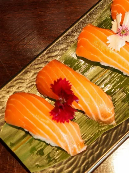 An overhead shot of our beautifully arranged Salmon Nigiri. The vibrant orange of the fish against the dark plate highlights its freshness and appeal.