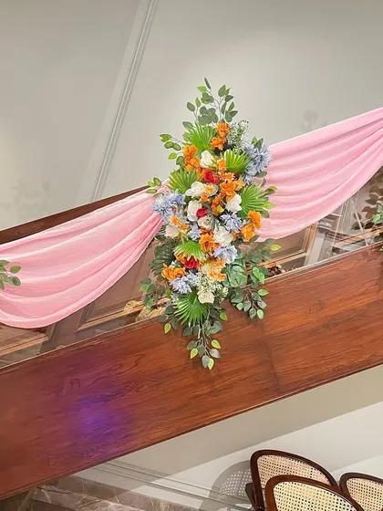 Staircase decoration with pink drapes and beautiful bouquets of artificial flowers, perfect for adding a festive touch to any venue.
