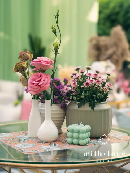 A tabletop detail from 'The Conservatory' baby shower, with delicate pink and purple flowers.