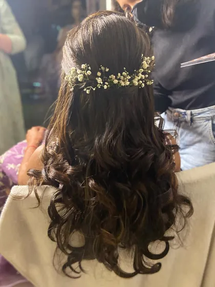 A simple and elegant half-up hairstyle with soft curls, finished with a baby's breath hair accessory.