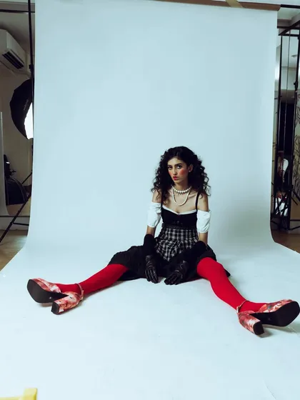 A behind-the-scenes style shot that sets the stage for the melancholic muse concept. The wide angle shows the studio environment and the model in character.