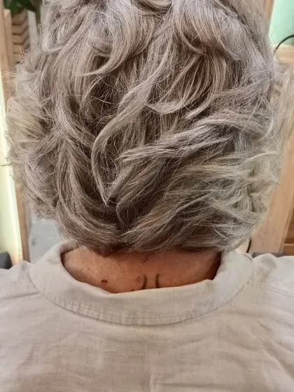 The back view of a stylish haircut for mature hair. The soft curls and layers add volume and texture.