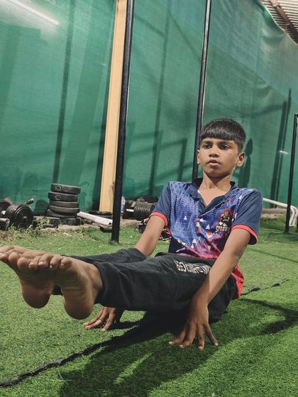 Perfecting his form, this young athlete demonstrates the L-sit. This exercise is a testament to the real-world strength we build in our kids' fitness programs.