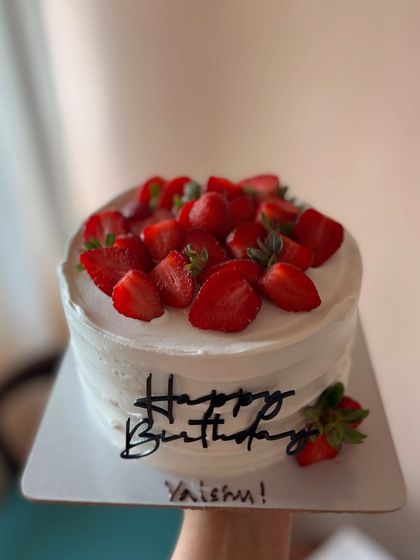 A simple and delicious vanilla cake with a rustic buttercream finish, topped with sliced fresh strawberries.