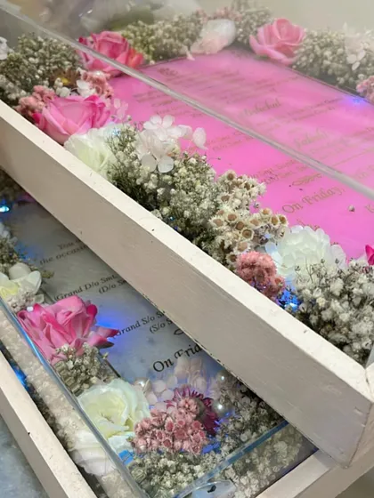 This image shows two of my boxed wedding invitations side by side, one with a pink theme and the other with a blue theme. Each invitation is nestled in a bed of dried flowers and comes with built in lights for a beautiful reveal.