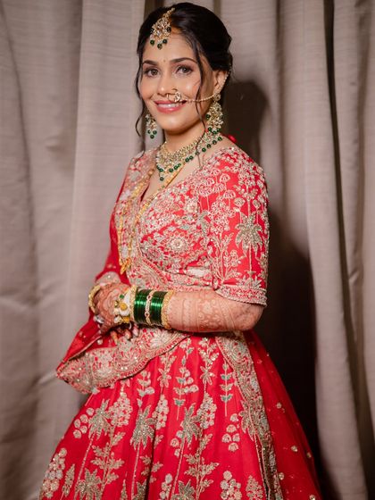 A full-length shot of the bride in her stunning red embroidered lehenga. The elegant updo and confident smile complete this perfect look for a wedding reception.