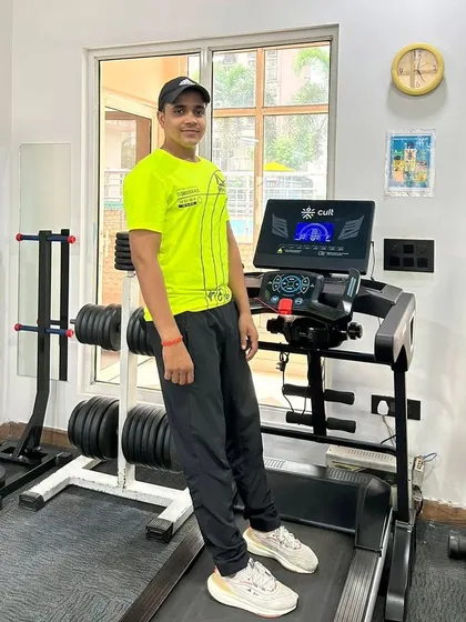 Standing on the treadmill in a bright shirt, bringing energy to the gym.