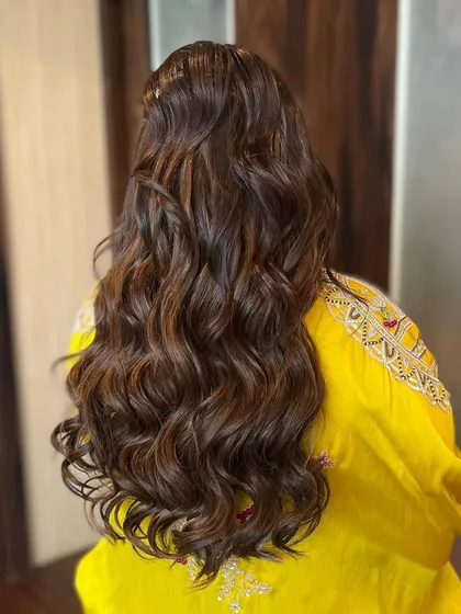 A close up on the texture of the soft waves. The highlights in the hair are beautifully defined by the curls, adding depth and dimension.