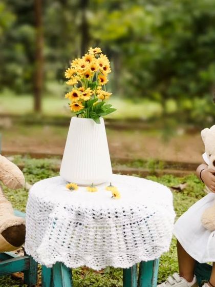 A whimsical outdoor tea party for one. A little girl enjoys a moment with her teddy bear during her second birthday celebration.