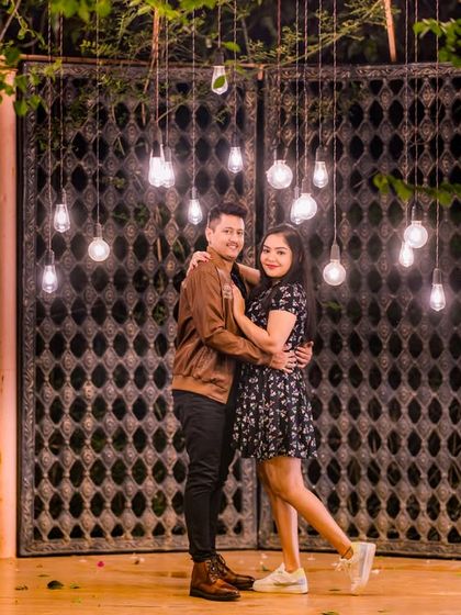The rustic gate and hanging bulbs provide a cool, industrial-chic backdrop for this couple's evening portrait.