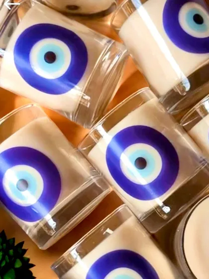 A collection of scented candles in glass jars featuring the evil eye design. These are perfect for creating a serene ambiance during meditation or as part of a wellness-themed festive hamper.